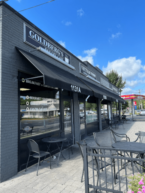 Exterior view of a storefront with awnings, featuring "Goldberg's" and "Vietnamese Cuisine" signs, and outdoor seating.