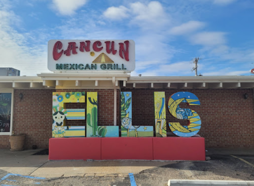 Colorful sign for Cancun Mexican Grill featuring the word "ELLIS" in large, artistic letters against a brick wall.