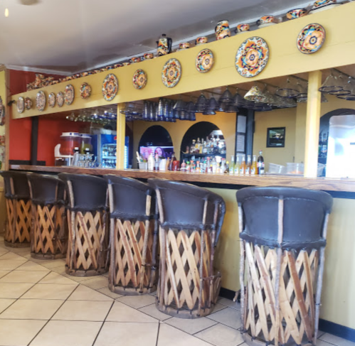 A colorful bar area with wooden stools and decorative plates on the wall, featuring a vibrant and inviting atmosphere.