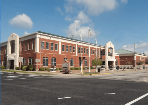 A modern brick building with flags outside, set against a clear blue sky.