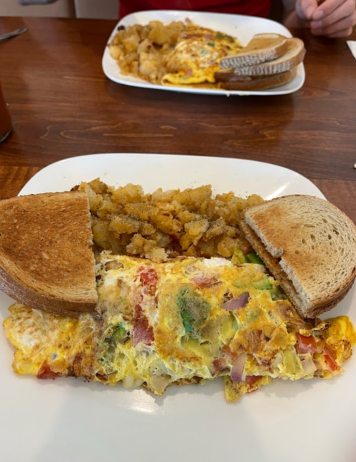 A plate with a vegetable omelet, hash browns, and two slices of toasted bread.
