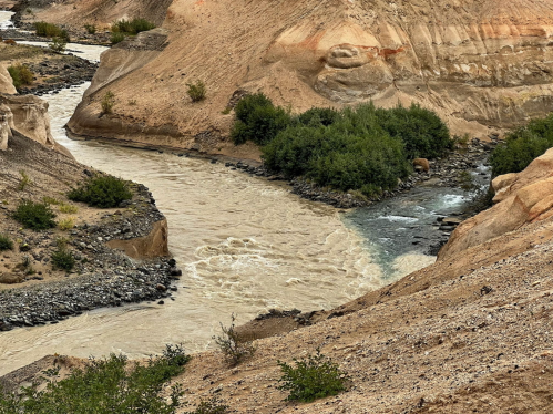 A winding river flows through a dry, rocky landscape with sparse greenery along its banks.