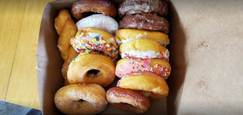A box filled with assorted donuts, including glazed, chocolate, and sprinkled varieties.