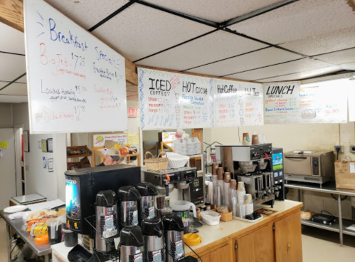 A cozy café interior with a coffee station, menus on the wall, and breakfast and lunch options displayed.