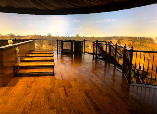 A spacious wooden deck with steps, overlooking a scenic landscape under a clear sky.