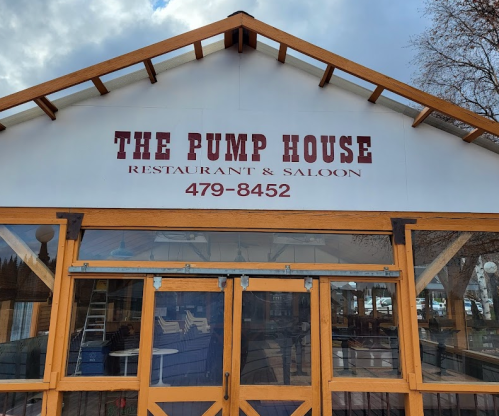 Sign for "The Pump House Restaurant & Saloon" with a phone number, featuring a wooden structure and large windows.