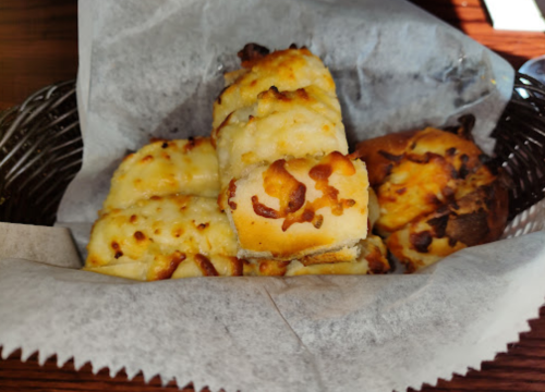 A basket of cheesy garlic breadsticks, golden and toasted, served on parchment paper.
