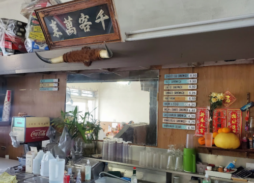 A rustic restaurant counter with a mirror, menu board, and decorative items, including a sign and a cow horn.