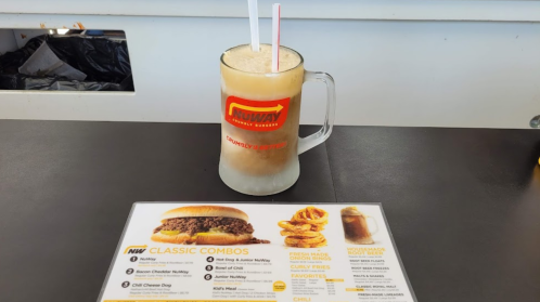 A frosty mug of root beer floats next to a menu featuring classic combo meals at NuWay.
