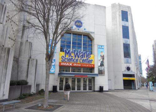 Entrance of the McWane Science Center with a large IMAX Dome Theater sign, surrounded by trees and buildings.