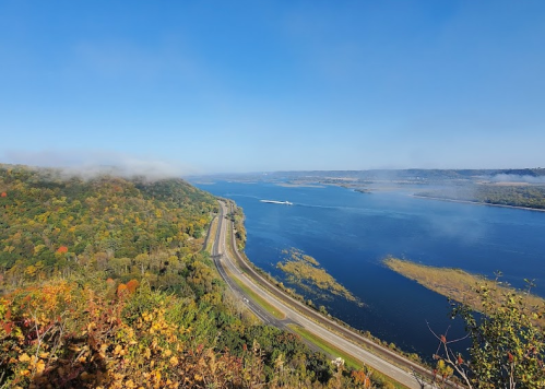 A scenic view of a river winding through lush, colorful hills under a clear blue sky.