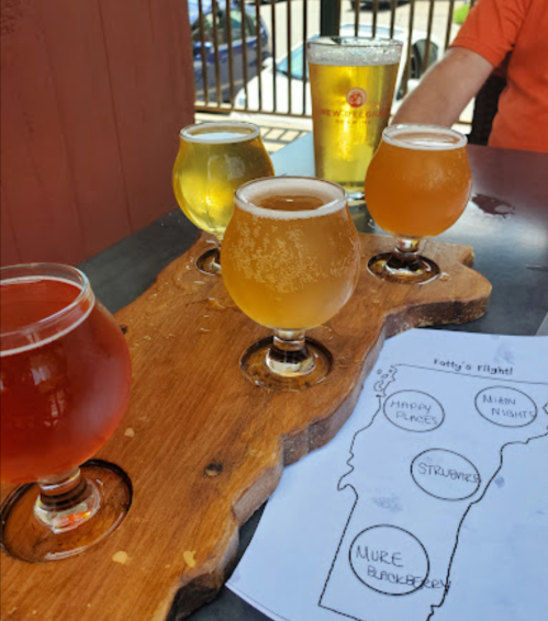 A wooden flight board with five small beer glasses and a menu titled "Fatty's Flight" on a table.