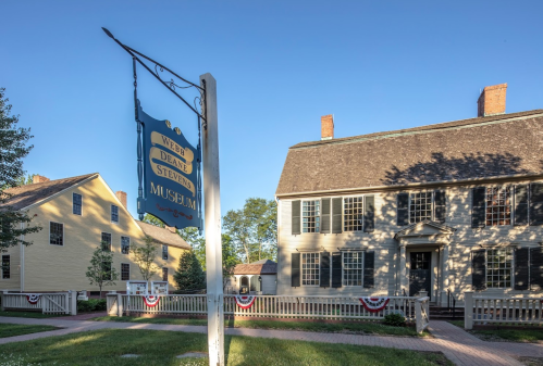 Sign for the Webb-Deane-Stevens Museum in front of historic buildings, decorated with patriotic bunting.