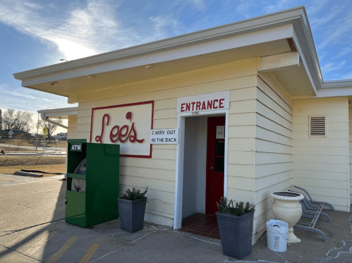 A small building with a sign reading "Lee's," featuring an entrance and an ATM nearby.