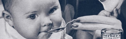 A baby being fed with a spoon, with a can of Gerber's Junior Meats in the foreground.