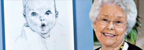 A smiling elderly woman stands next to a sketch of a baby, showcasing a warm and nostalgic atmosphere.