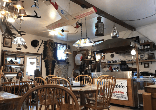 Cozy restaurant interior with wooden tables, eclectic decor, and a vintage airplane hanging from the ceiling.