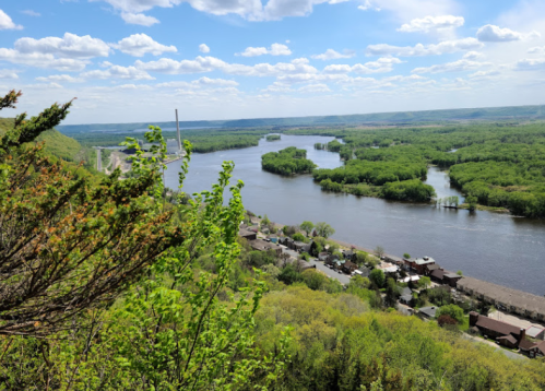 A scenic view of a river winding through lush greenery under a partly cloudy sky.