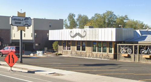 Exterior of Handle Bar restaurant with a mustache logo, bike decorations, and a construction sign in front.