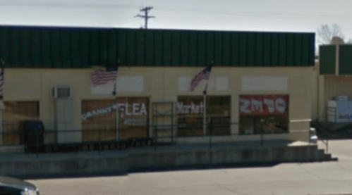 Exterior of Granny's Flea Market with American flags, featuring large windows and a green roof.