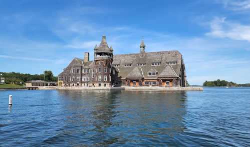 A large, historic mansion with a tower, surrounded by water and blue skies.