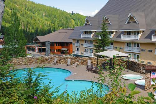 A scenic view of a hotel with a pool surrounded by trees and mountains in the background.