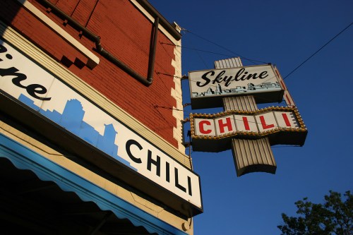 Sign for Skyline Chili against a clear blue sky, featuring a retro design and city skyline silhouette.