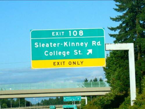 Green highway exit sign for Sleater-Kinney Rd and College St, indicating "Exit Only" for Exit 108.