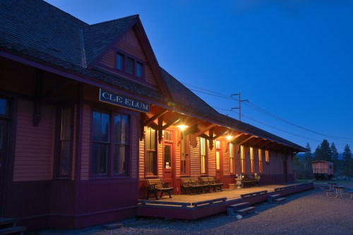 Historic Cle Elum train station at dusk, featuring warm lights and a charming wooden exterior.