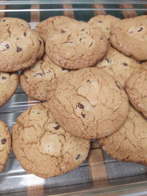 A close-up of freshly baked chocolate chip cookies on a cooling rack.