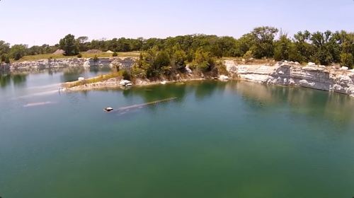 A serene lake surrounded by lush greenery and rocky cliffs under a clear blue sky.