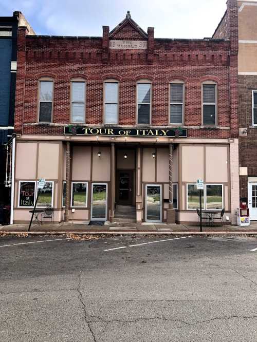 Historic brick building with "Tour of Italy" sign, featuring large windows and a staircase entrance.