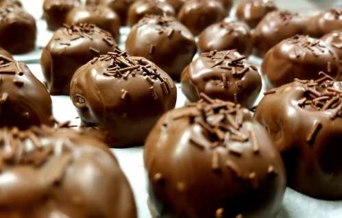 A close-up of chocolate-covered treats topped with chocolate sprinkles, arranged neatly on a tray.
