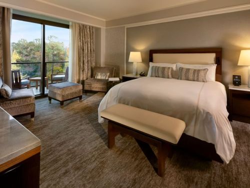 A cozy hotel room featuring a king-sized bed, seating area, and large windows with a view.