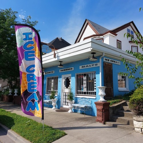 A colorful ice cream shop with a large "Ice Cream" banner, featuring outdoor seating and a bright blue exterior.