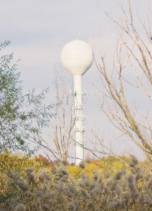 A white water tower labeled "UNION" rises above trees in a rural landscape under a cloudy sky.