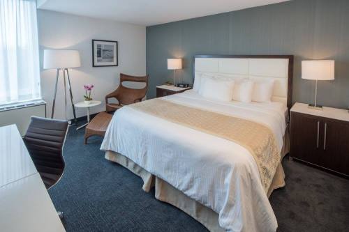 A modern hotel room featuring a king-sized bed, desk, chair, and soft lighting.