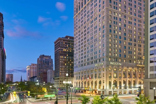 A cityscape at dusk featuring the Westin hotel, with traffic and buildings illuminated in the background.