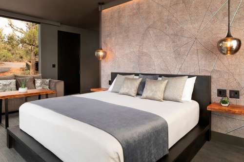 Modern hotel room featuring a king-sized bed, stylish decor, and large windows with natural light.