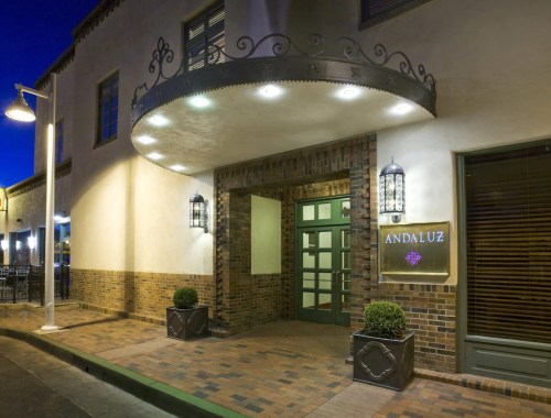 Entrance of the Andaluz building, featuring a decorative awning, lanterns, and potted plants at dusk.
