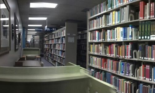 A view of a library aisle lined with bookshelves and study tables, creating a quiet study environment.