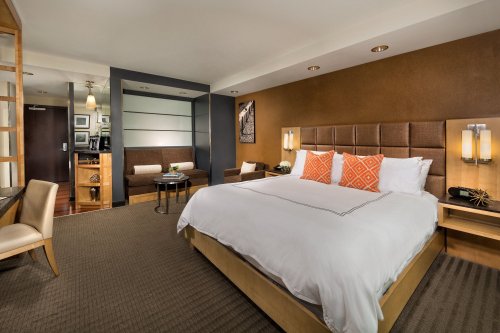 A modern hotel room featuring a king-sized bed, stylish decor, and a cozy seating area.
