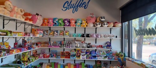 A colorful display of toys and stuffed animals on shelves in a bright store.
