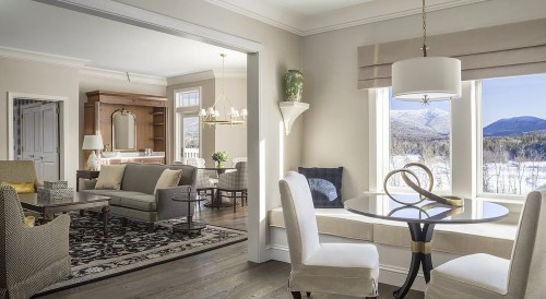 Bright, modern living space with a cozy seating area, dining table, and large windows showcasing a mountain view.