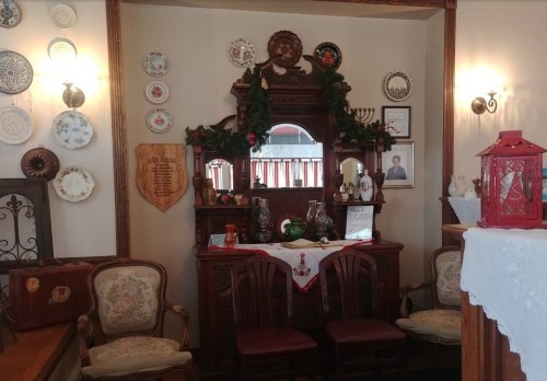 A cozy room featuring an ornate wooden dresser, decorative plates on the wall, and festive holiday decor.