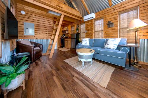 Cozy cabin interior with wooden walls, a blue sofa, a coffee table, and a small kitchen area. Warm, inviting atmosphere.