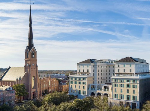 A historic church with a tall spire next to a modern building under a clear blue sky.
