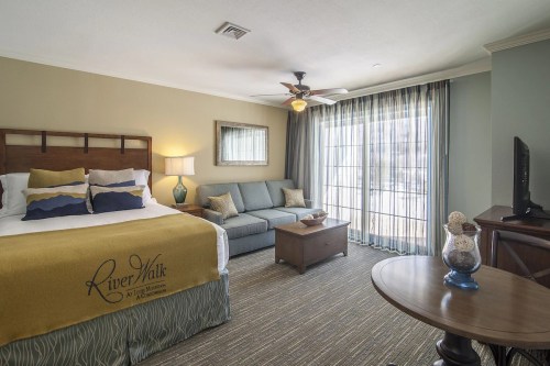 Cozy hotel room featuring a bed, sofa, coffee table, and large windows with natural light.