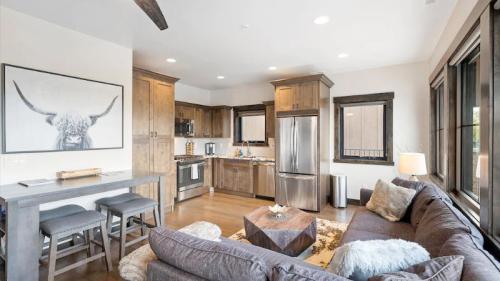 Modern kitchen and living area with wooden cabinets, a cozy sofa, and a large window, featuring a bull artwork on the wall.