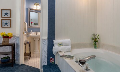 A cozy bathroom featuring a whirlpool tub, towels, wine glasses, and a view of a well-decorated vanity area.